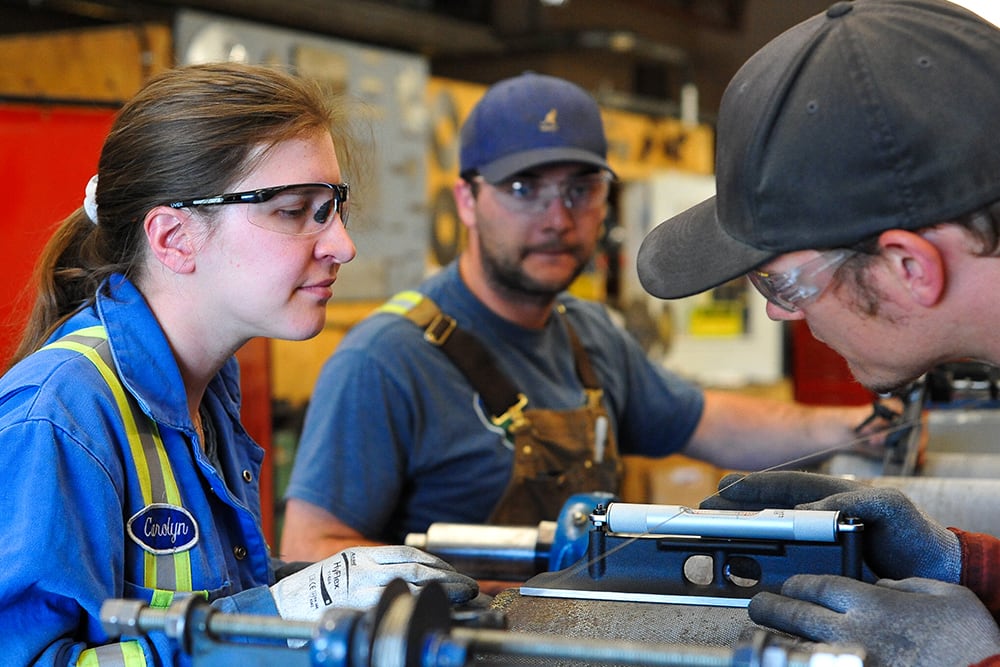 Three students observing machinery