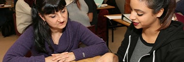 student and teacher looking down at book on desk